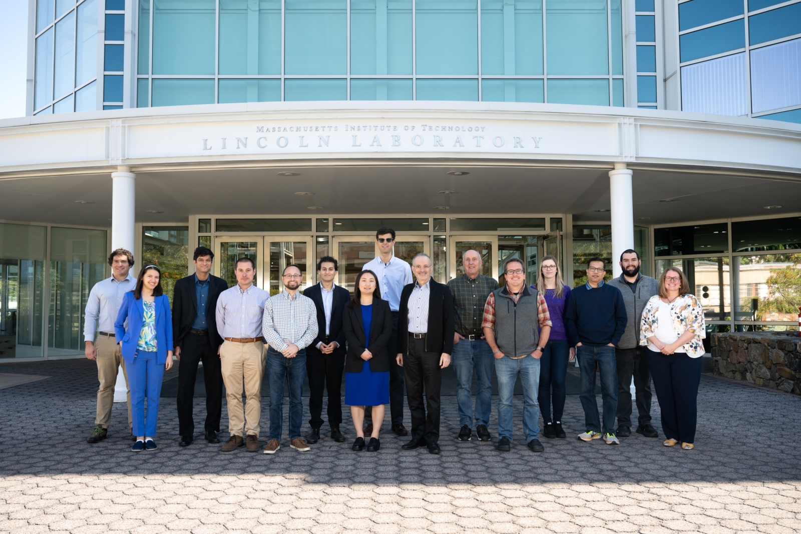 A group of 15 individuals representing the Laboratory's 3 R&D 100 winning technologies take a group photo in front of the Lincoln Laboratory main entrance. 
