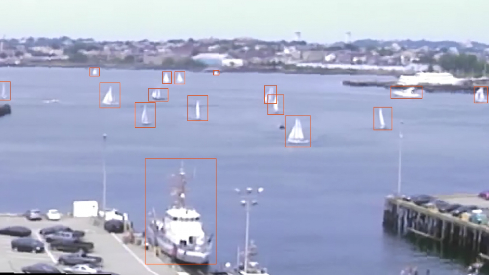a photo of boston harbor with several boats on the water; each boat has an orange box drawn around it as a 'detection'