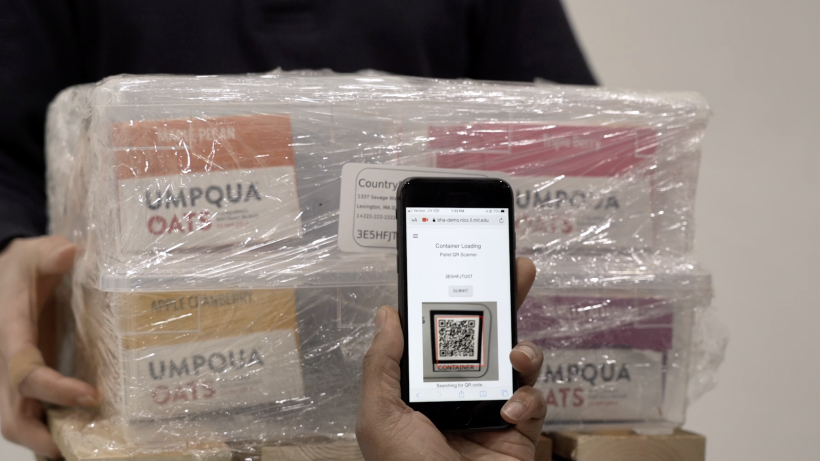 a photo of a person scanning a QR code, affixed to a small wrapped shipment of food, with a smartphone.