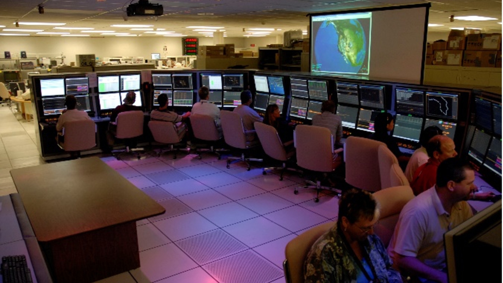 A dozen operators sit in front of computer screens. 