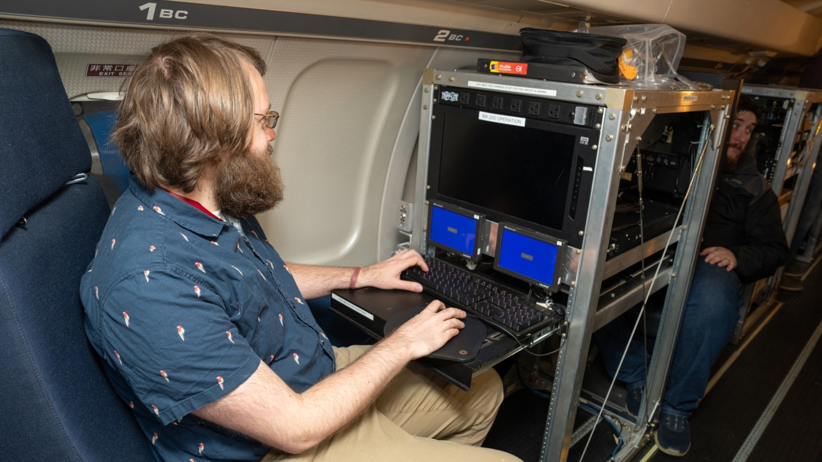 A man types on a keyboard onboard an aircraft.