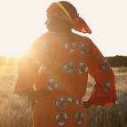 A photo of a woman with her hands on her hips, standing in a field.