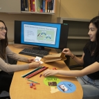 A photograph of Olivia Brown and Victoria Helus assembling kits for their artificial intelligence and machine learning workshops.