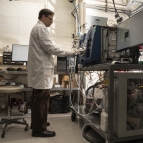 Laboratory staff member Ted Mendum stands while performing system checks on a mass spectrometer inside the laboratory. Photo: Glen Cooper