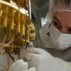 A researcher makes adjustments to a dilution refrigerator, a large piece of hardware for cooling quantum systems.