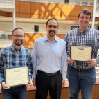 Three staff members pose for a group photo in a sunny atrium.